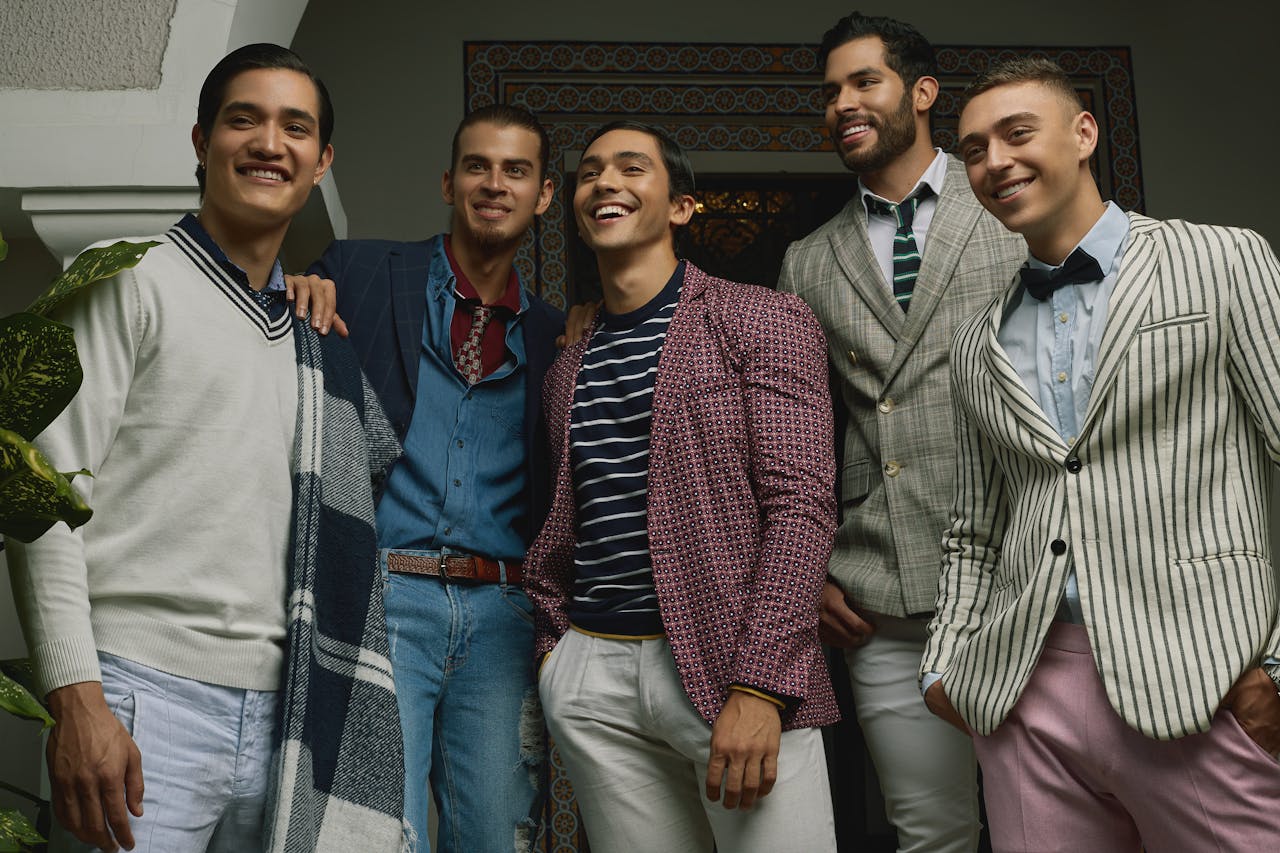 Five men in fashionable attire posing indoors, exuding confidence and style.