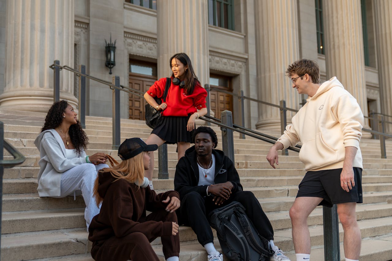 A diverse group of young adults in casual attire socializing on urban steps.
